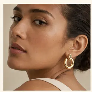 Solis Sculptural Gold Hoops styled on a model from a second angle